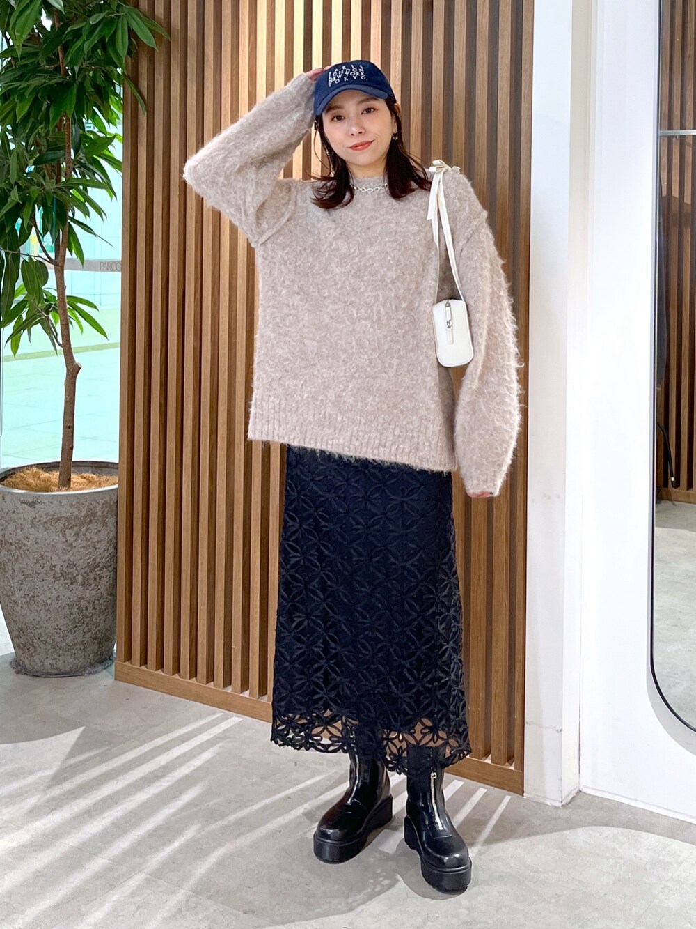 ホワイト系のショルダーバッグ、ベージュ系のニット/セーター、ブラック系のスカートを着用したレディースの冬コーディネートの2枚目の写真