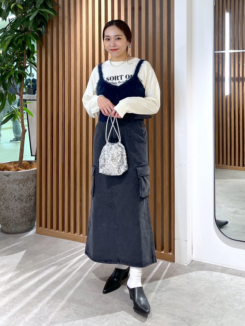 ベージュ系のTシャツ/カットソー、ブルー系のベスト、シルバー系のハンドバッグを着用したレディースの冬コーディネートの2枚目の写真