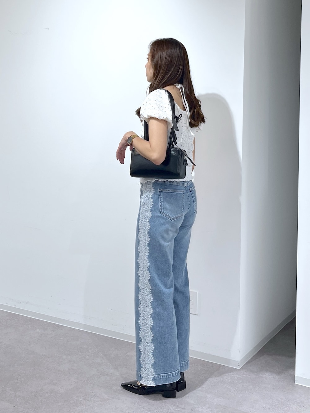 ブラック系のショルダーバッグ、ブラック系のパンプス、ブルー系のデニムパンツを着用したレディースの夏コーディネートの4枚目の写真