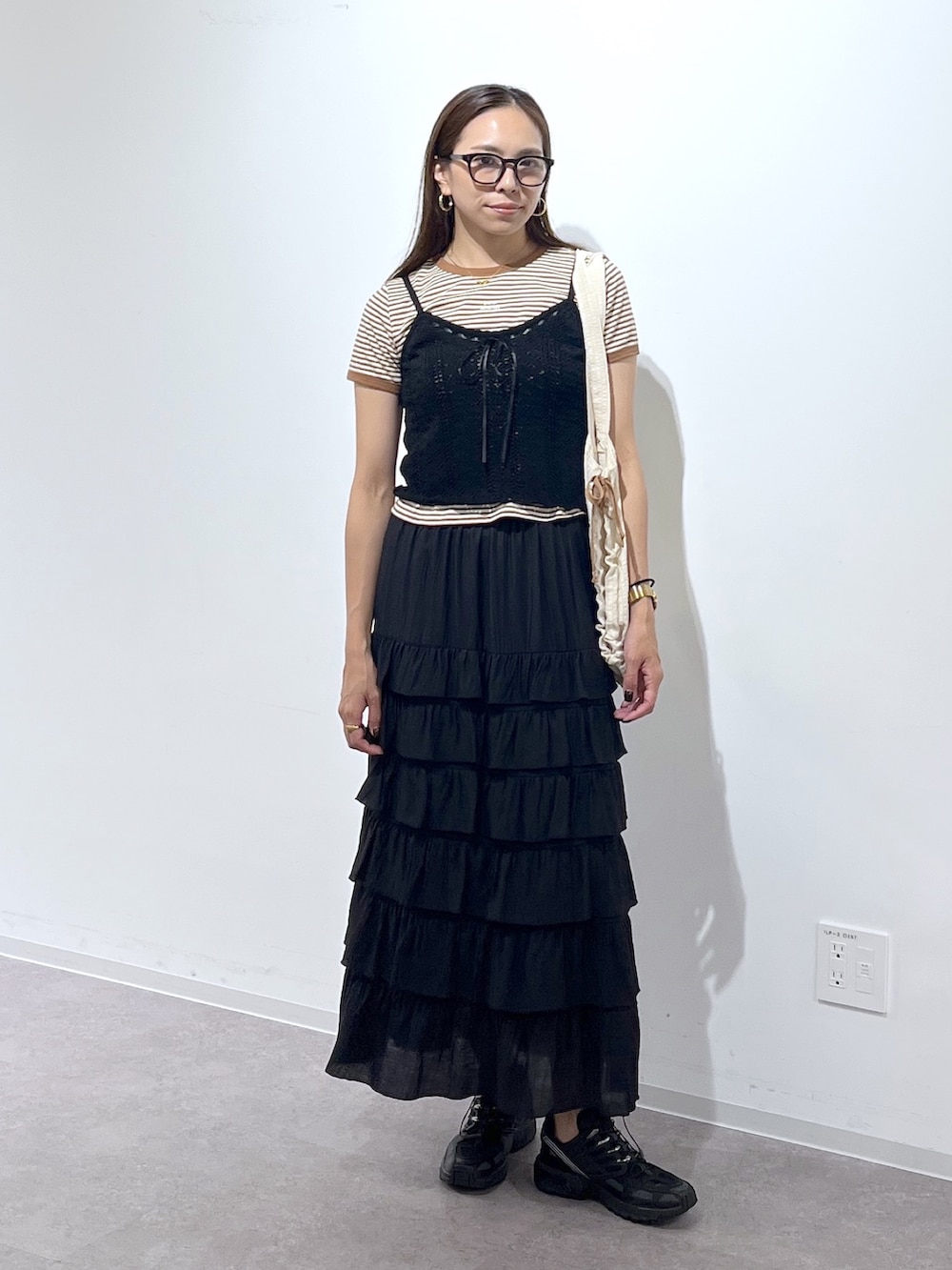 ホワイト系のトートバッグ、ブラック系のスカート、ブラック系のニット/セーターを着用したレディースの夏コーディネートの2枚目の写真