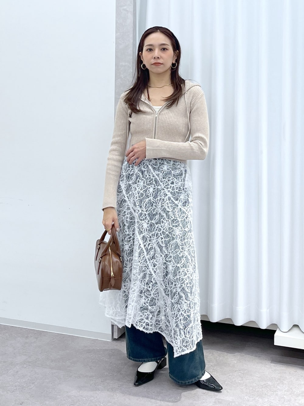 ベージュ系のニット/セーター、ブラウン系のハンドバッグ、ブルー系のデニムパンツを着用したレディースの冬コーディネートの4枚目の写真