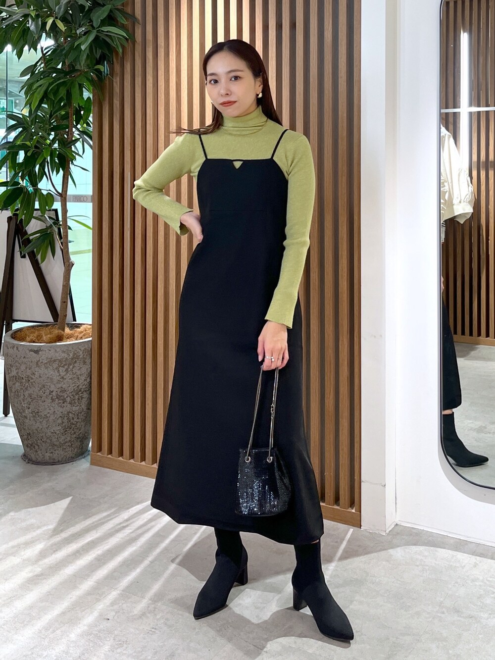 ブラック系のショルダーバッグ、ブラック系のワンピース、グリーン系のニット/セーターを着用したレディースの冬コーディネートの2枚目の写真