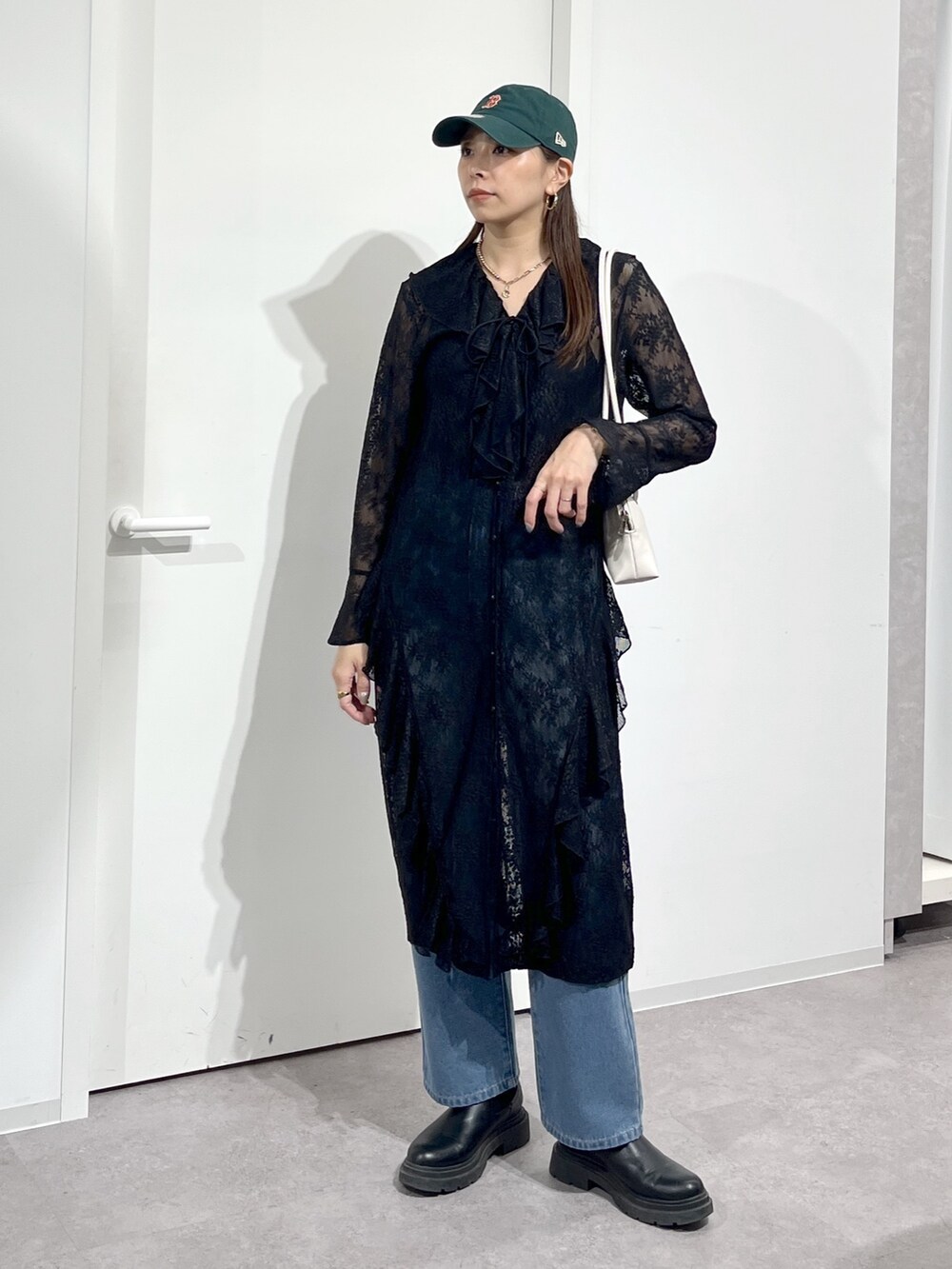 ホワイト系のショルダーバッグ、ブラック系のワンピース、ブルー系のデニムパンツを着用したレディースの冬コーディネートの3枚目の写真