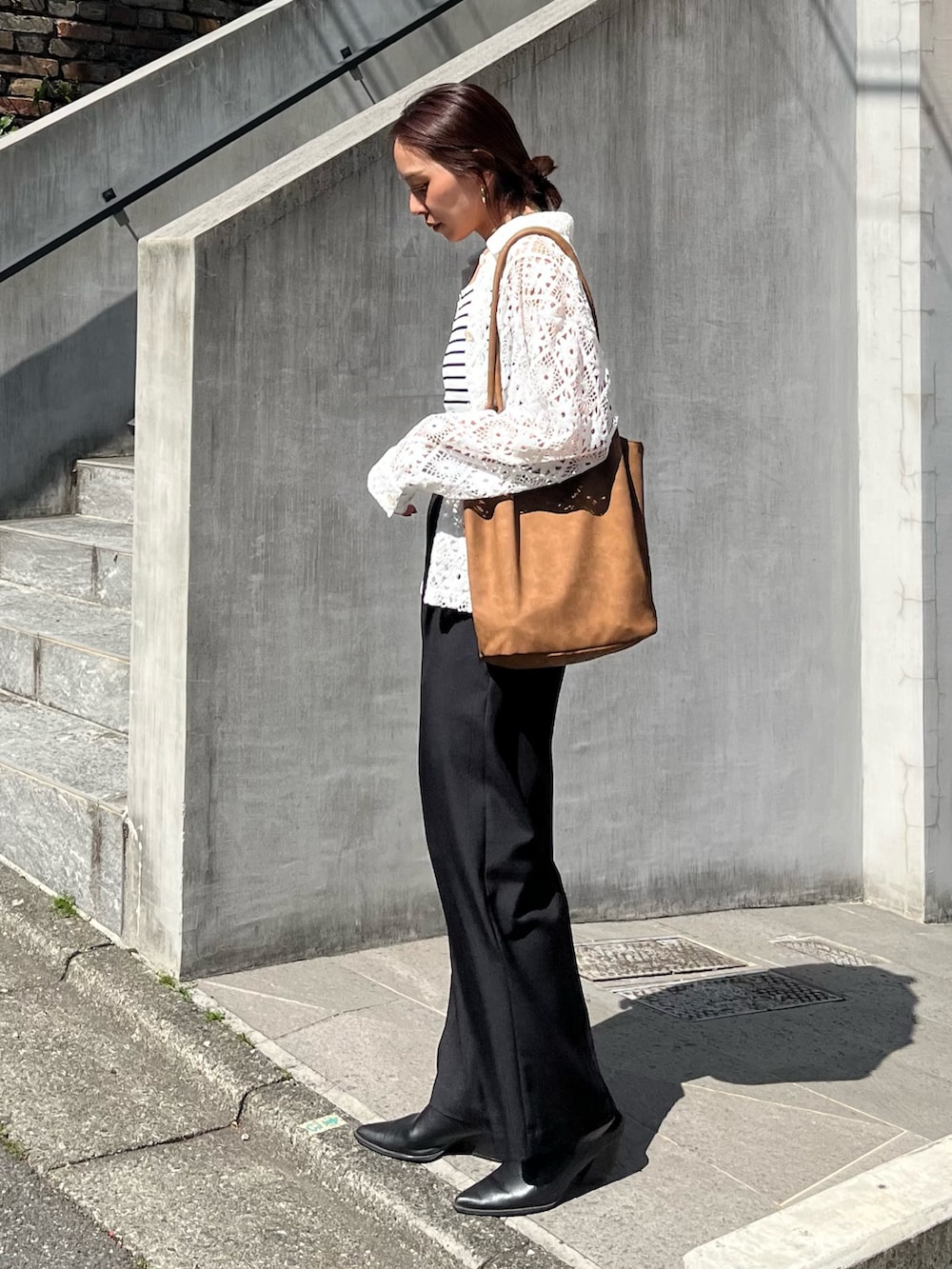 ブラック系のスラックス、ブラウン系のトートバッグ、ホワイト系のブルゾンを着用したレディースの春コーディネートの3枚目の写真