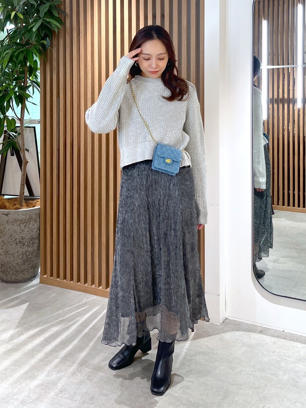 グレー系のニット/セーター、ブルー系のショルダーバッグ、ブラック系のスカートを着用したレディースの冬コーディネートの3枚目の写真