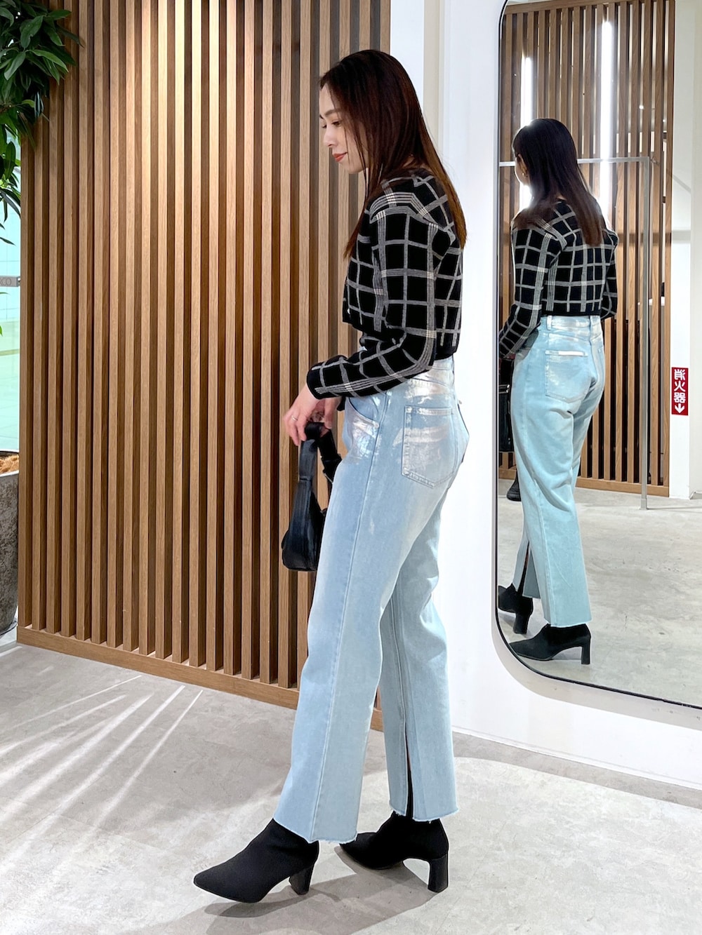 ブルー系のデニムパンツ、ブラック系のニット/セーター、ブラック系のショルダーバッグを着用したレディースの冬コーディネートの5枚目の写真