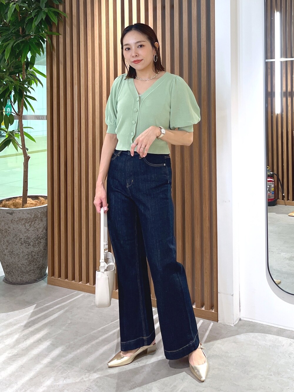 グリーン系のカーディガン/ボレロ、グレー系のショルダーバッグ、ブルー系のデニムパンツを着用したレディースの春コーディネートの3枚目の写真