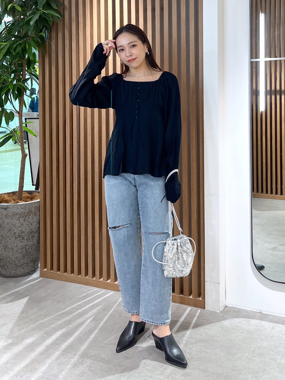 ブラック系のシャツ/ブラウス、ブルー系のデニムパンツ、シルバー系のハンドバッグを着用したレディースの冬コーディネートの2枚目の写真