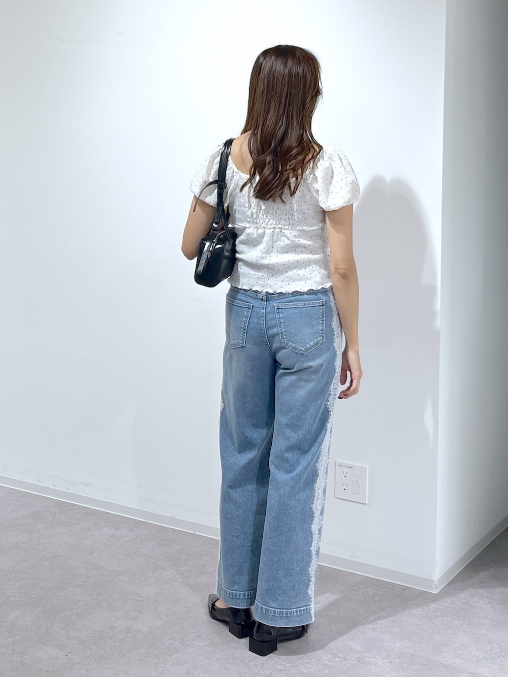 ブラック系のショルダーバッグ、ブラック系のパンプス、ブルー系のデニムパンツを着用したレディースの夏コーディネートの5枚目の写真