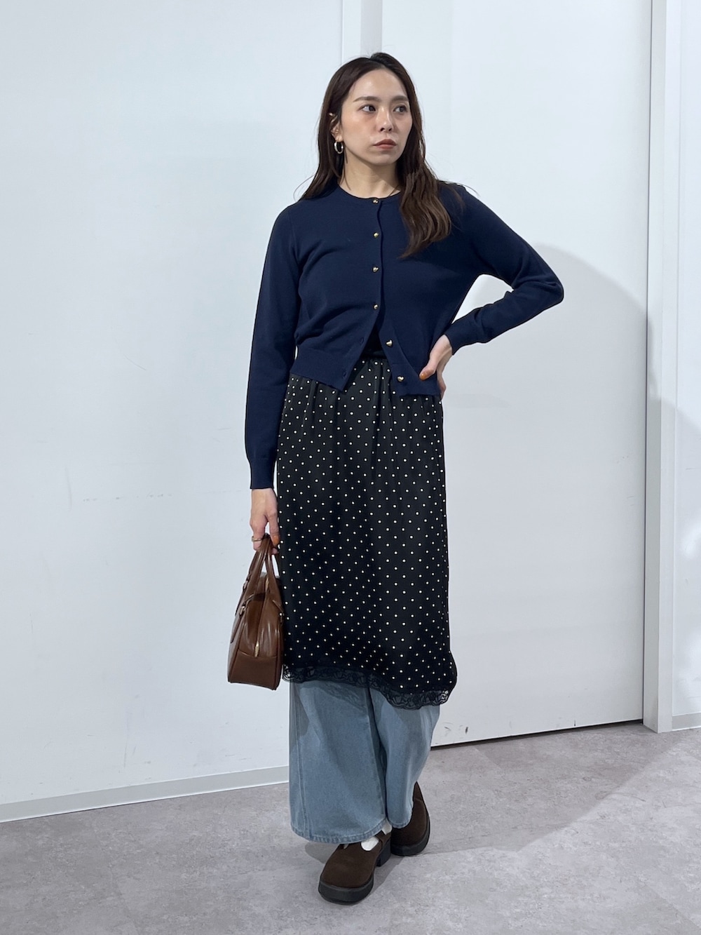 ブルー系のデニムパンツ、ブラウン系のハンドバッグ、ブラック系のスカートを着用したレディースの冬コーディネートの7枚目の写真