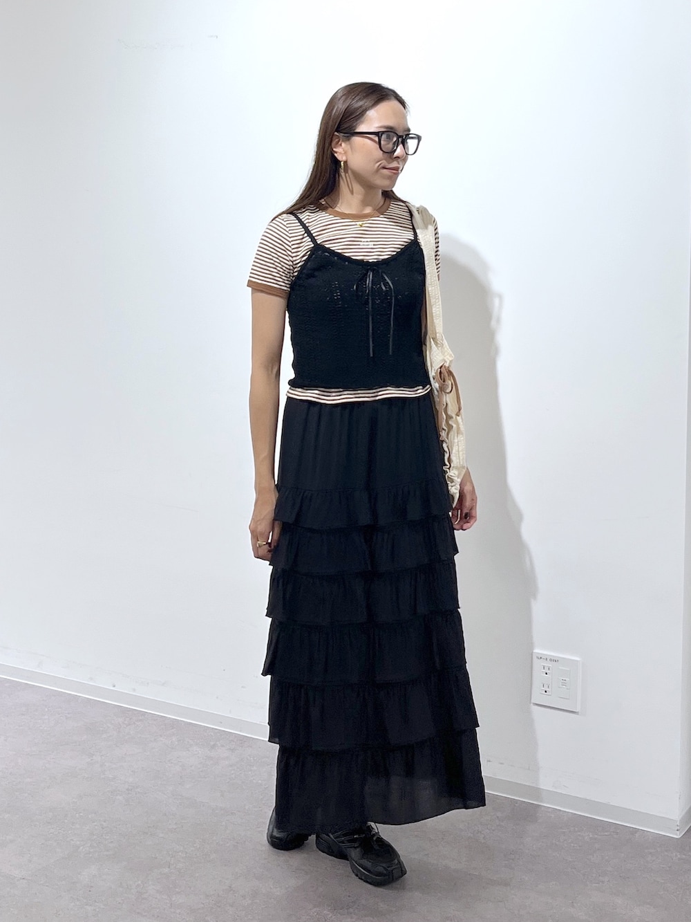 ホワイト系のトートバッグ、ブラック系のスカート、ブラック系のニット/セーターを着用したレディースの夏コーディネートの7枚目の写真