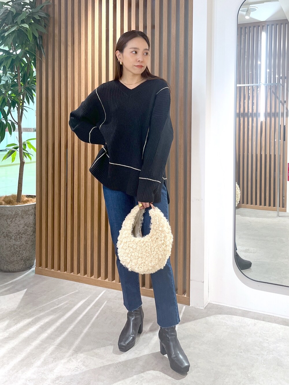 ブラック系のニット/セーター、ベージュ系のショルダーバッグ、ブルー系のデニムパンツを着用したレディースの秋コーディネートの2枚目の写真