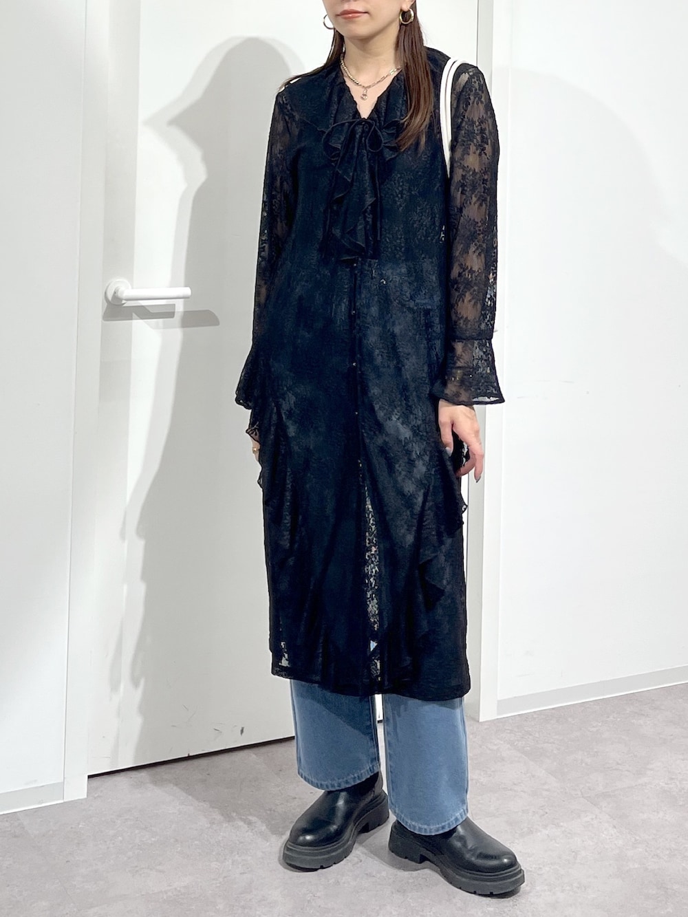 ホワイト系のショルダーバッグ、ブラック系のワンピース、ブルー系のデニムパンツを着用したレディースの冬コーディネートの4枚目の写真