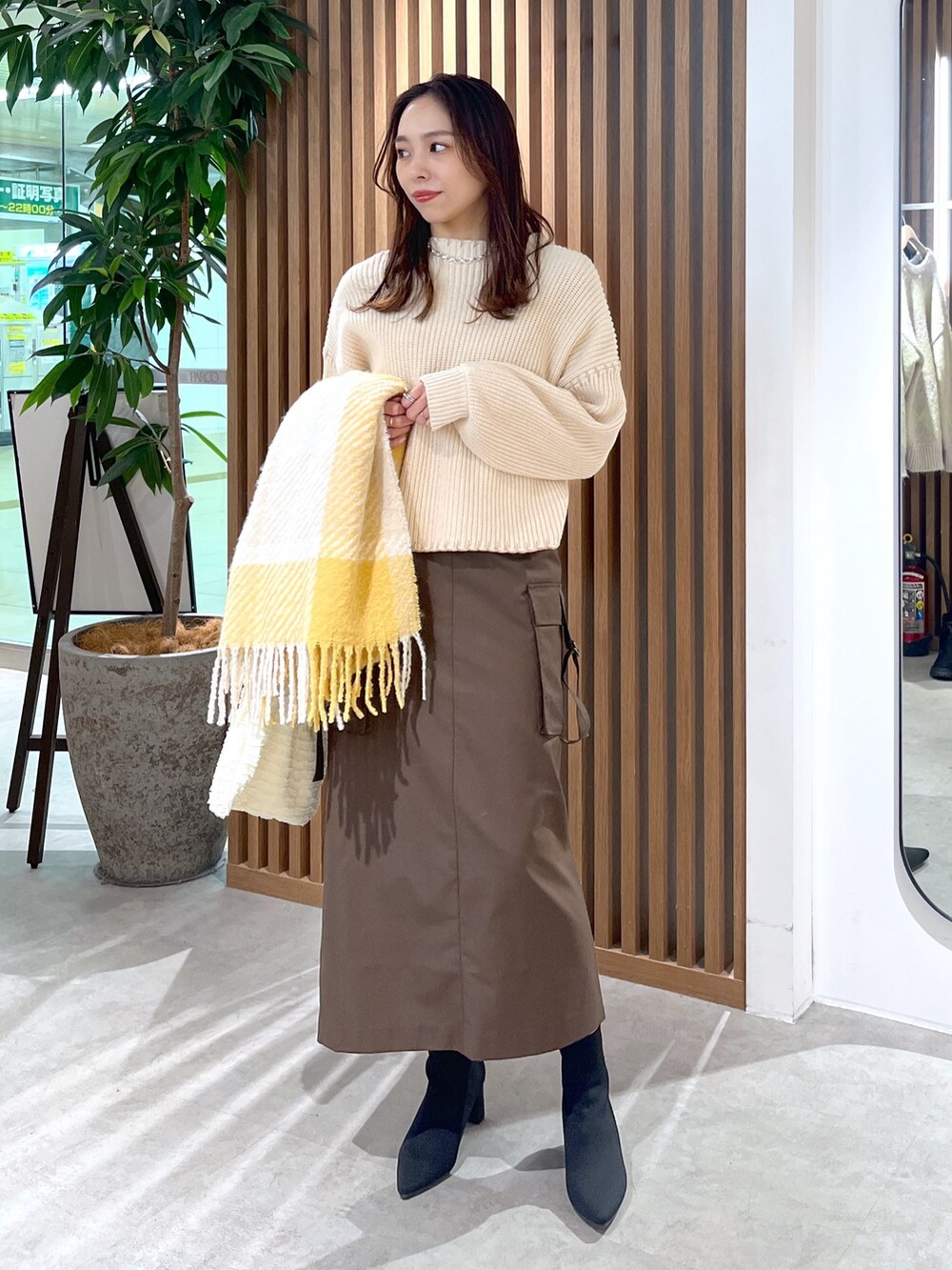 ブラウン系のスカート、ホワイト系のトートバッグ、ホワイト系のニット/セーターを着用したレディースの冬コーディネートの3枚目の写真