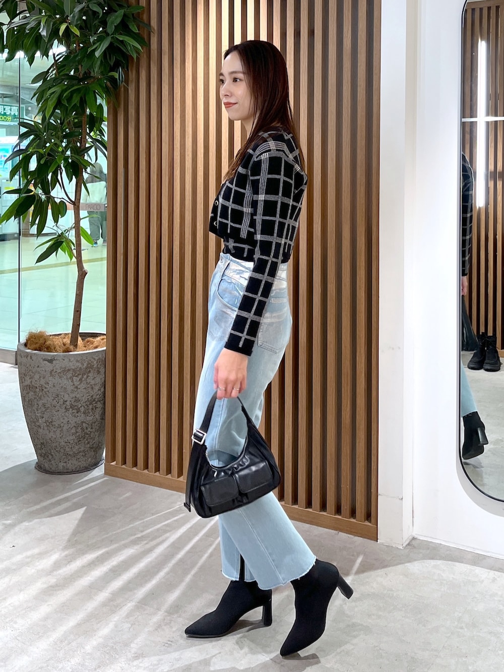 ブルー系のデニムパンツ、ブラック系のニット/セーター、ブラック系のショルダーバッグを着用したレディースの冬コーディネートの4枚目の写真