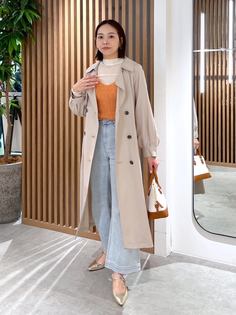 ブラウン系のショルダーバッグ、ホワイト系のTシャツ/カットソー、オレンジ系のベストを着用したレディースの春コーディネートの4枚目の写真