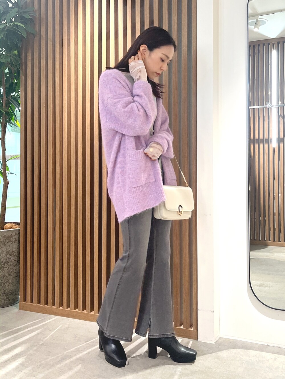 パープル系のカーディガン/ボレロ、ホワイト系のショルダーバッグ、ブラック系のデニムパンツを着用したレディースの秋コーディネートの4枚目の写真