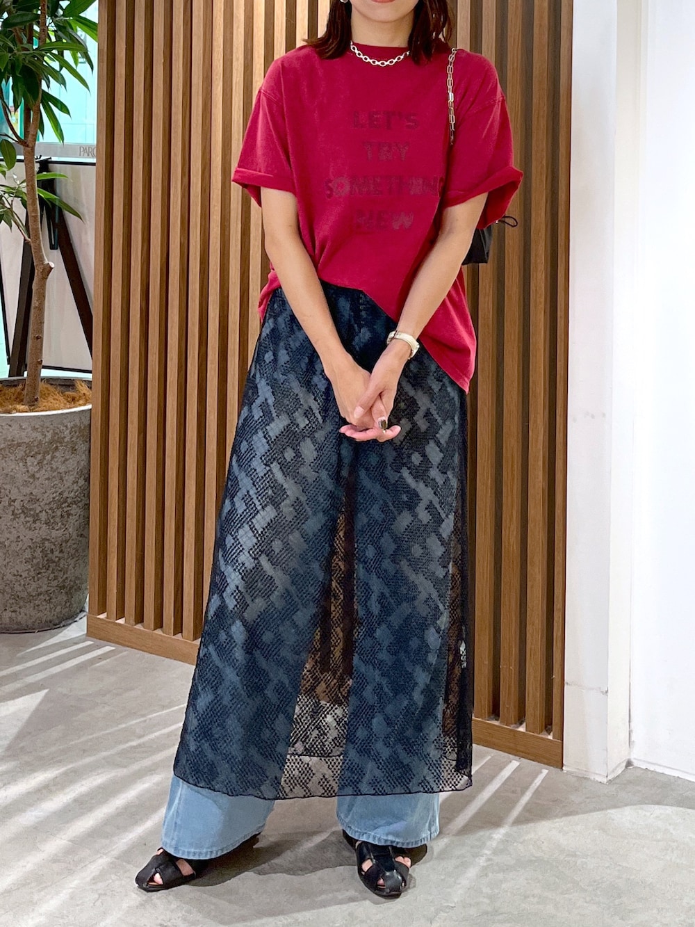 レッド系のTシャツ/カットソー、ブラック系のハンドバッグ、ブルー系のデニムパンツを着用したレディースの夏コーディネートの3枚目の写真