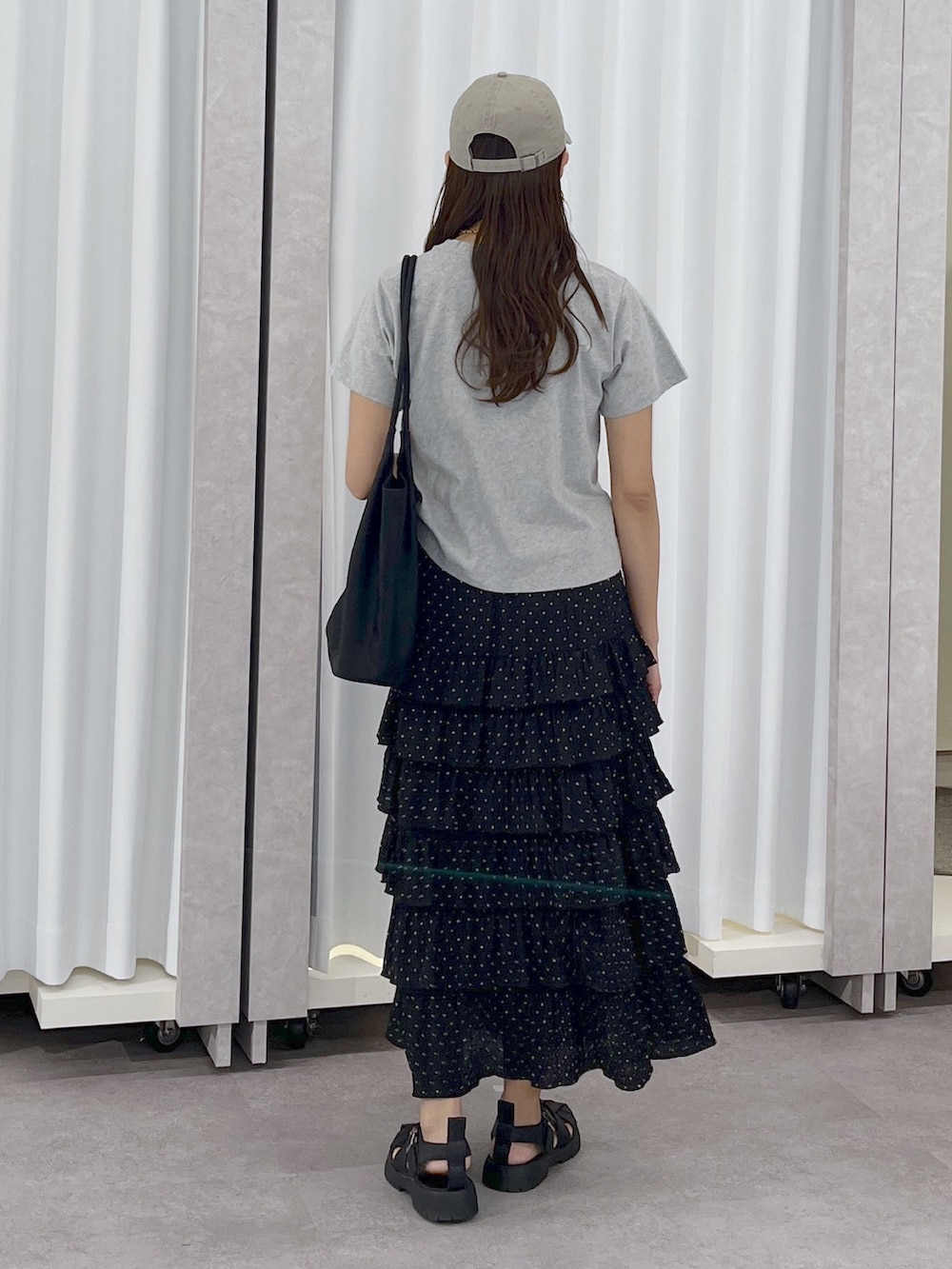 ブラック系のトートバッグ、ブラック系のスカート、グレー系のTシャツ/カットソーを着用したレディースの春コーディネートの4枚目の写真