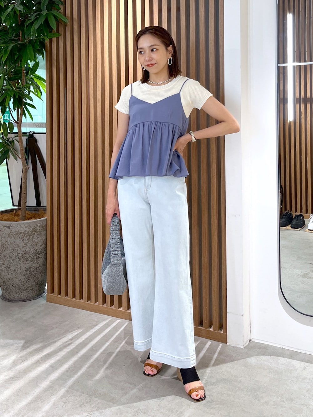 ホワイト系のニット/セーター、ブルー系のシャツ/ブラウス、ブルー系のデニムパンツを着用したレディースの夏コーディネートの3枚目の写真