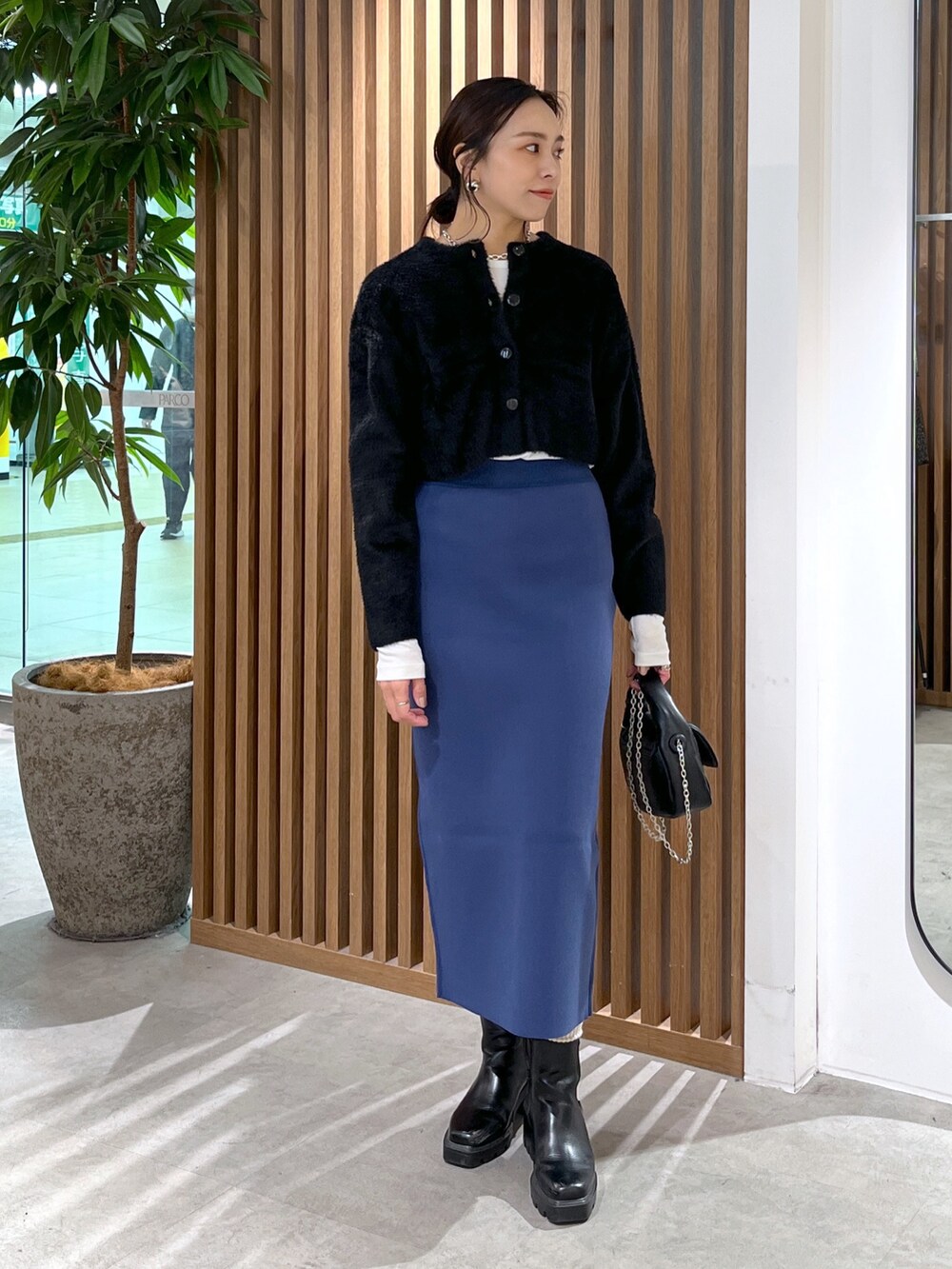 ブラック系のカーディガン/ボレロ、ブラック系のショルダーバッグ、ブルー系のスカートを着用したレディースの冬コーディネートの4枚目の写真