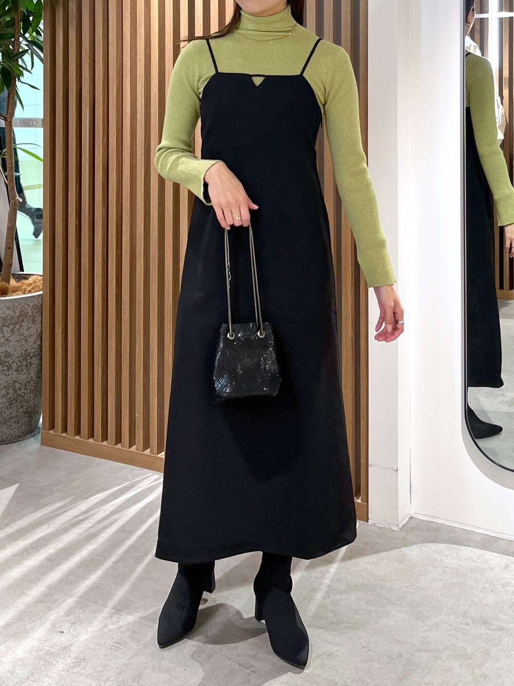 ブラック系のショルダーバッグ、ブラック系のワンピース、グリーン系のニット/セーターを着用したレディースの冬コーディネートの5枚目の写真