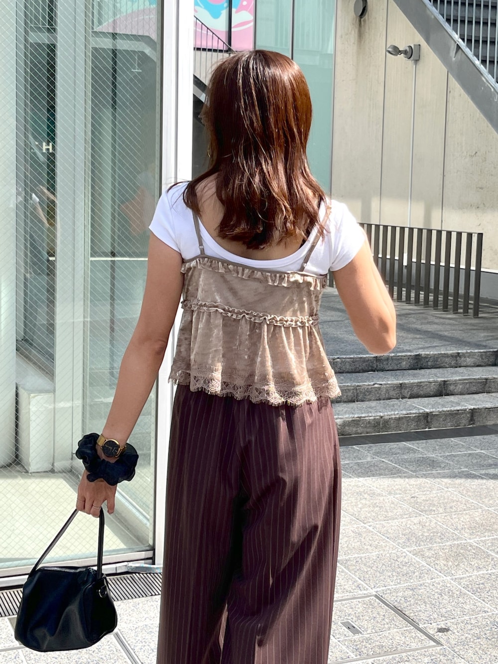 ブラック系のハンドバッグ、ブラック系のパンプス、ホワイト系のTシャツ/カットソーを着用したレディースの夏コーディネートの6枚目の写真
