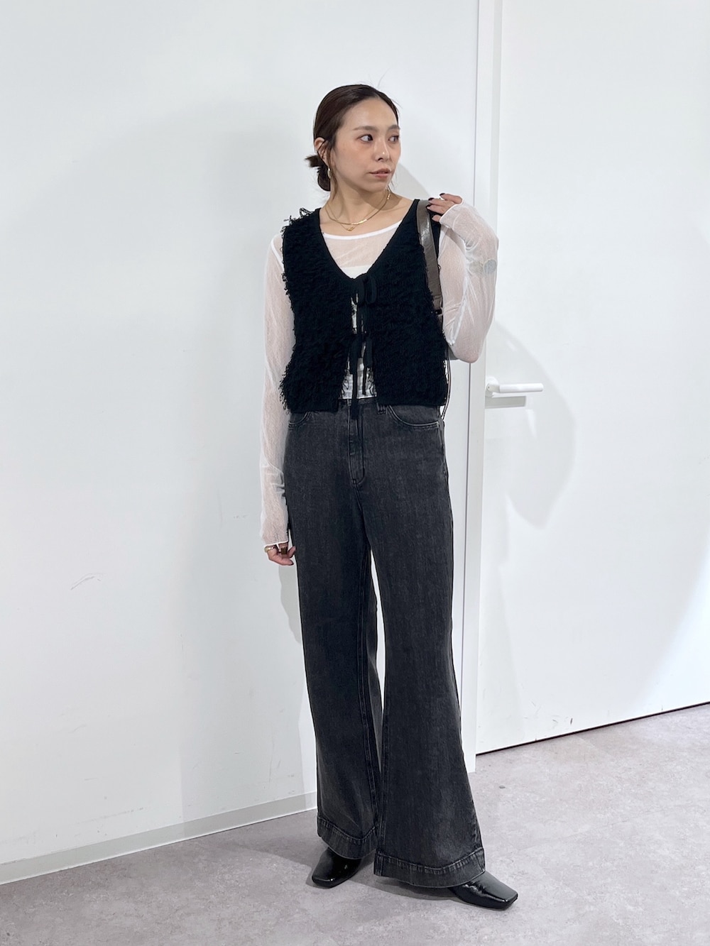 ブラウン系のショルダーバッグ、ブラック系のニット/セーター、ホワイト系のTシャツ/カットソーを着用したレディースの夏コーディネートの2枚目の写真