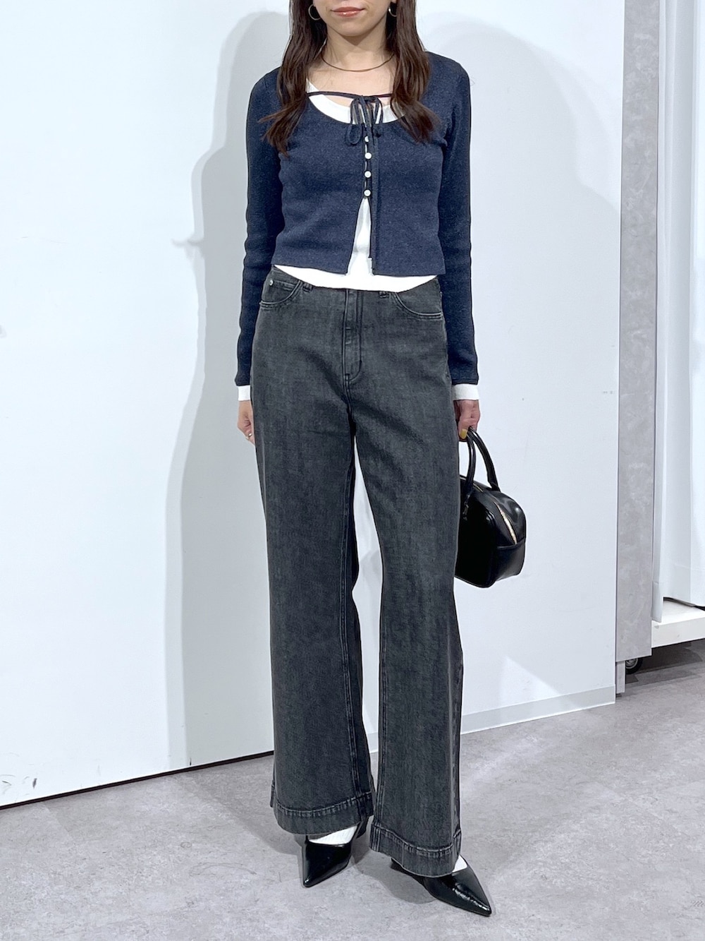 ブラック系のハンドバッグ、ブラック系のパンプス、ブラック系のデニムパンツを着用したレディースの春コーディネートの7枚目の写真