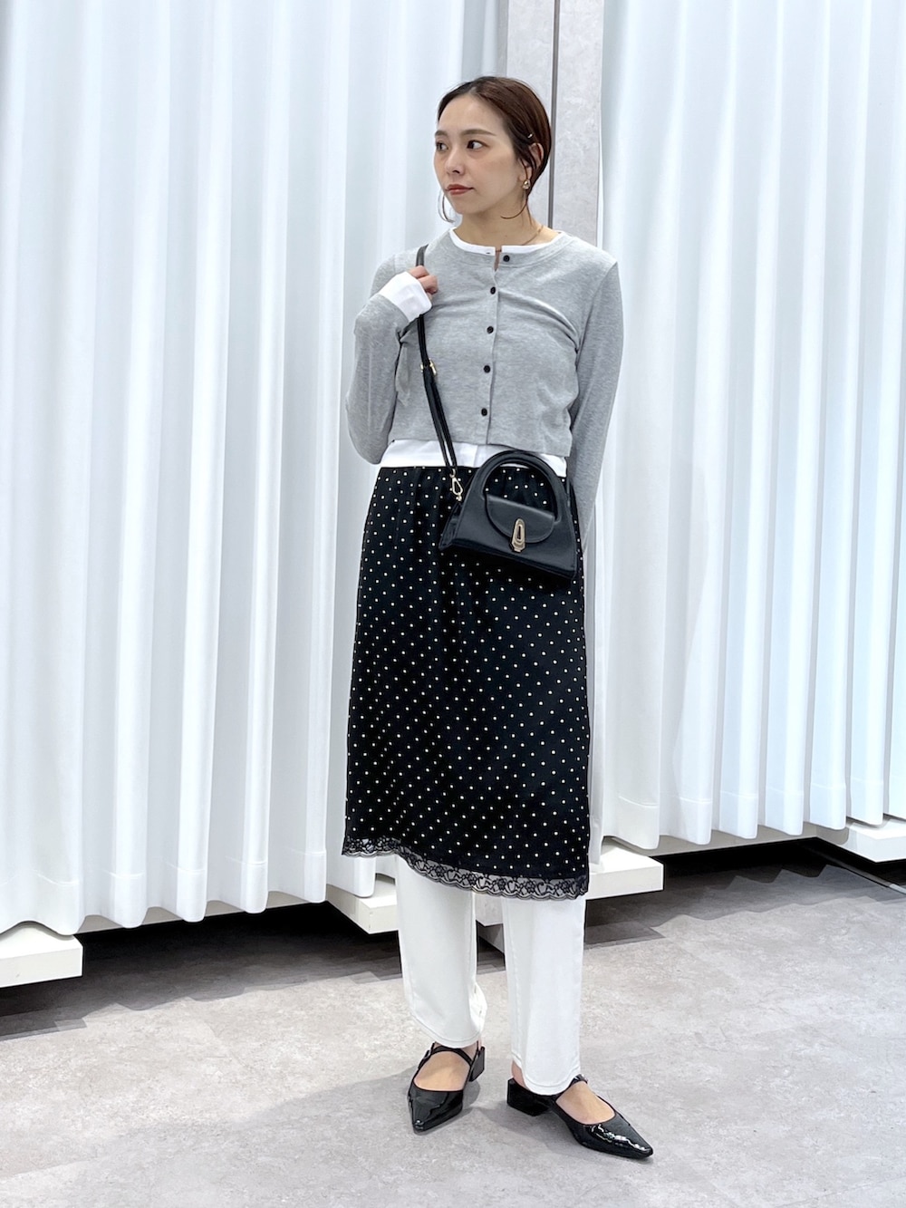 ブラック系のスカート、グレー系のTシャツ/カットソー、ホワイト系のデニムパンツを着用したレディースの春コーディネートの2枚目の写真