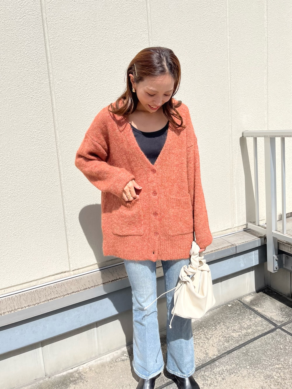 オレンジ系のカーディガン/ボレロ、ブルー系のデニムパンツ、ホワイト系のトートバッグを着用したレディースの秋コーディネートの3枚目の写真