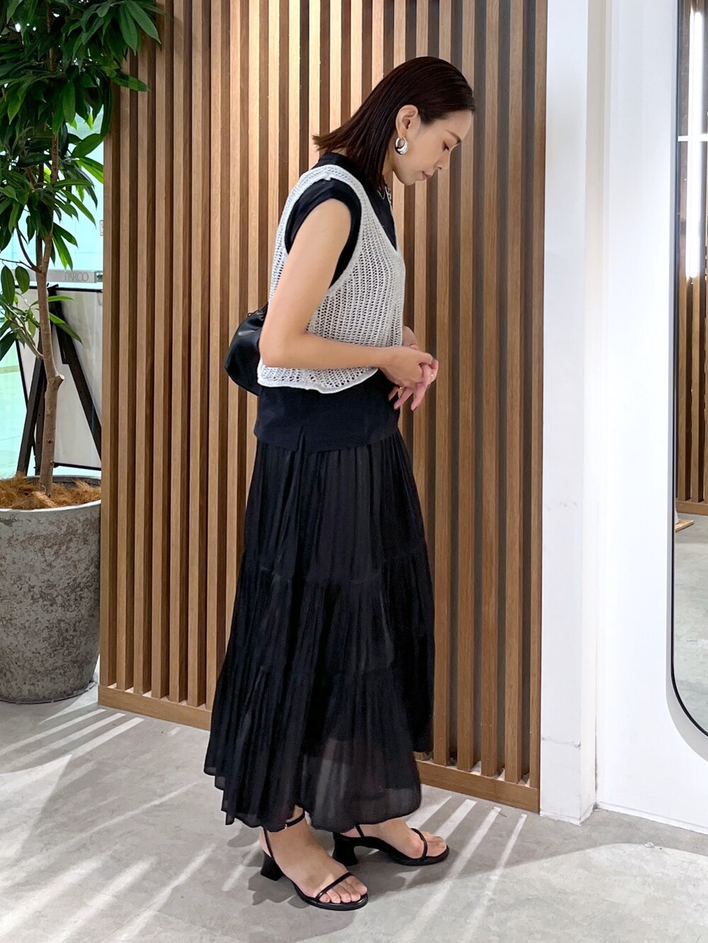 ブラック系のサンダル、ブラック系のスカート、ブラック系のショルダーバッグを着用したレディースの夏コーディネートの4枚目の写真