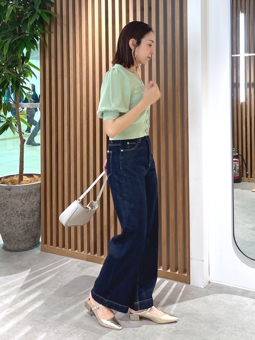 グリーン系のカーディガン/ボレロ、グレー系のショルダーバッグ、ブルー系のデニムパンツを着用したレディースの春コーディネートの6枚目の写真