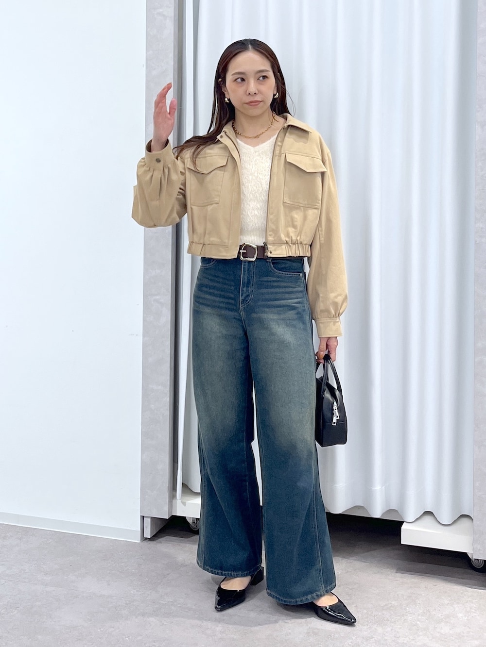 ベージュ系のブルゾン、ホワイト系のニット/セーター、ブルー系のデニムパンツを着用したレディースの春コーディネートの2枚目の写真