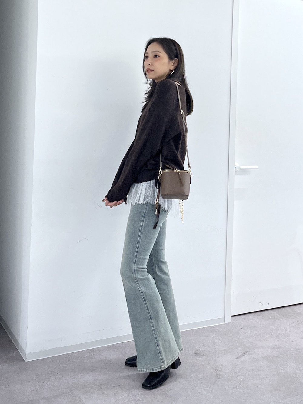 ブラウン系のショルダーバッグ、ブラック系のブーツ、ブルー系のデニムパンツを着用したレディースの秋コーディネートの9枚目の写真