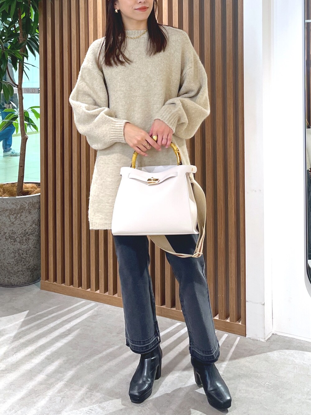 ベージュ系のワンピース、ブラック系のデニムパンツ、ホワイト系のショルダーバッグを着用したレディースの冬コーディネートの5枚目の写真