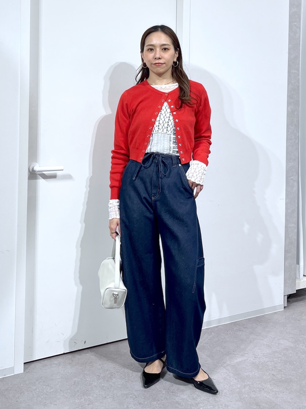 ホワイト系のTシャツ/カットソー、レッド系のニット/セーター、ブルー系のデニムパンツを着用したレディースの春コーディネートの2枚目の写真