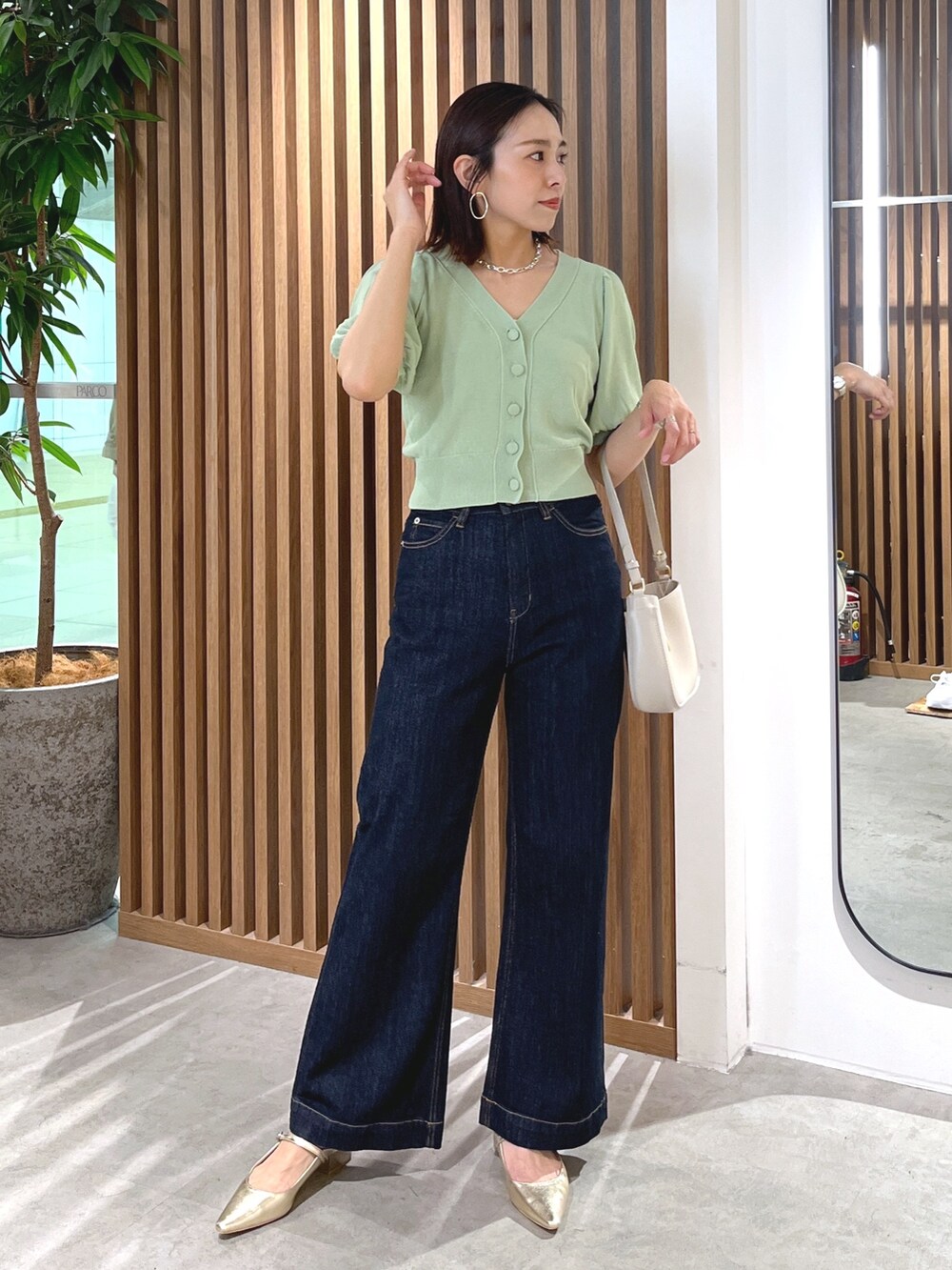 グリーン系のカーディガン/ボレロ、グレー系のショルダーバッグ、ブルー系のデニムパンツを着用したレディースの春コーディネートの2枚目の写真