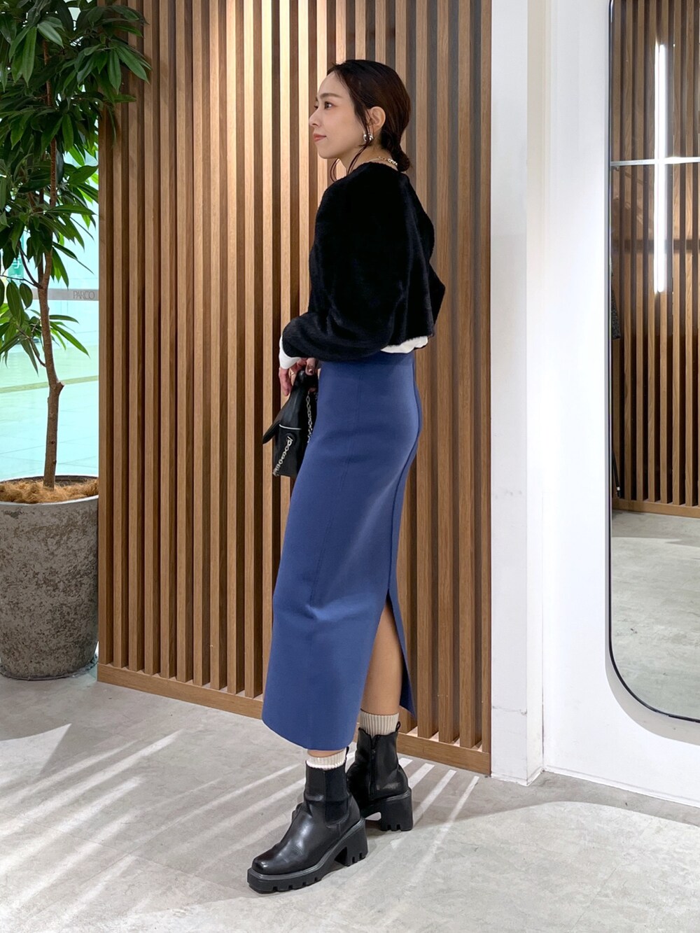 ブラック系のカーディガン/ボレロ、ブラック系のショルダーバッグ、ブルー系のスカートを着用したレディースの冬コーディネートの5枚目の写真