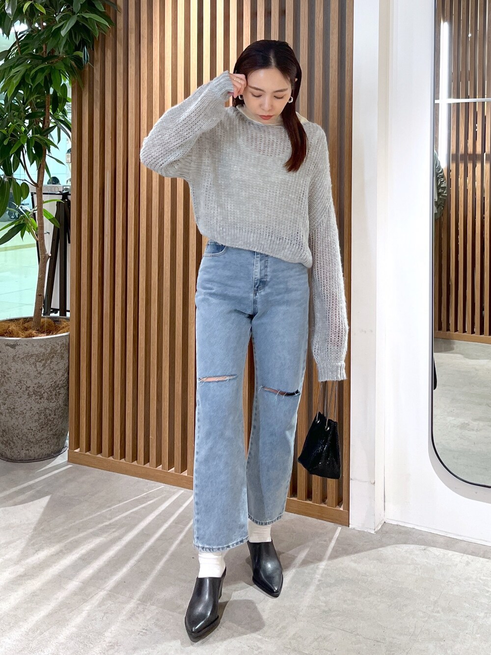 グレー系のニット/セーター、ホワイト系のTシャツ/カットソー、ブルー系のデニムパンツを着用したレディースの冬コーディネートの3枚目の写真