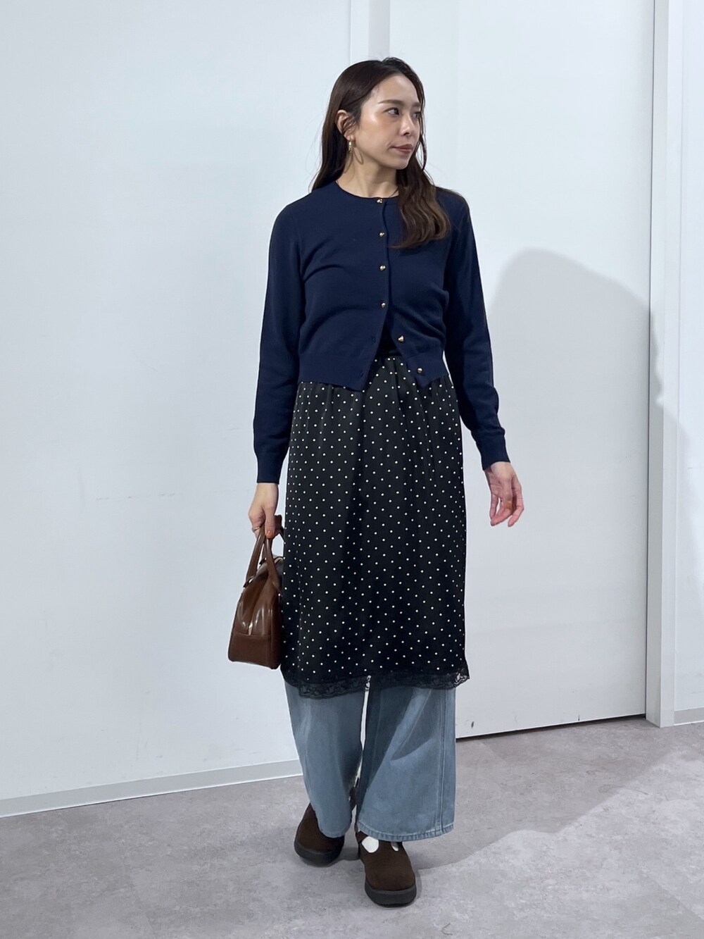 ブルー系のデニムパンツ、ブラウン系のハンドバッグ、ブラック系のスカートを着用したレディースの冬コーディネートの3枚目の写真