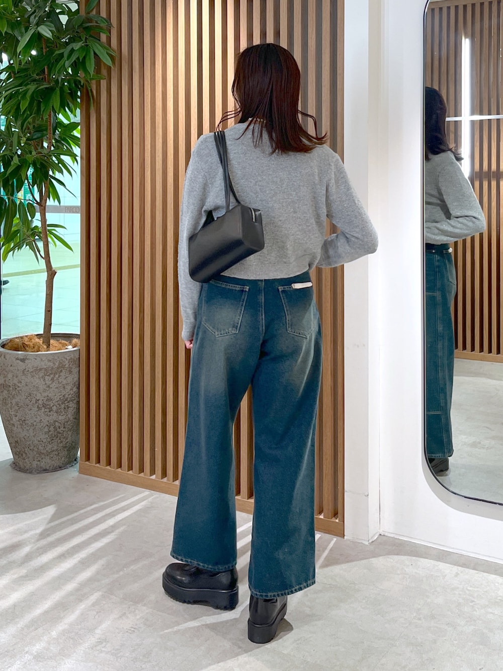 グレー系のワンピース、ブルー系のデニムパンツ、ブラック系のブーツを着用したレディースの冬コーディネートの5枚目の写真
