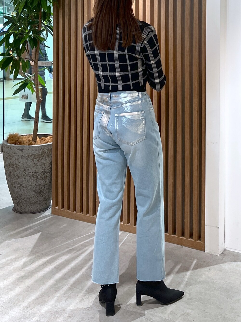 ブルー系のデニムパンツ、ブラック系のニット/セーター、ブラック系のショルダーバッグを着用したレディースの冬コーディネートの7枚目の写真