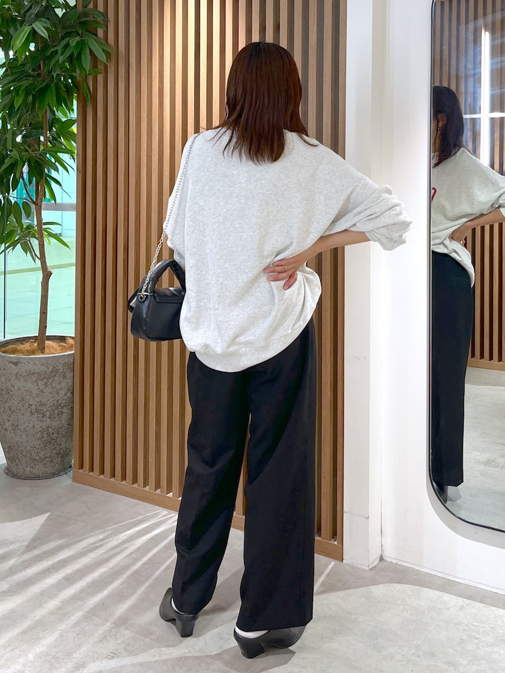 ホワイト系のスウェット、ブラック系のショルダーバッグ、ブラック系のスラックスを着用したレディースの秋コーディネートの5枚目の写真
