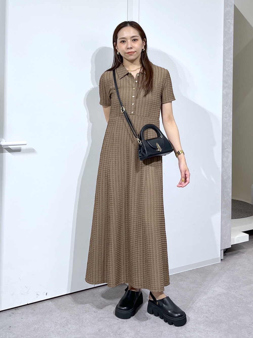 ブラック系のショルダーバッグ、ブラック系のサンダル、ブラウン系のワンピースを着用したレディースの春コーディネートの2枚目の写真