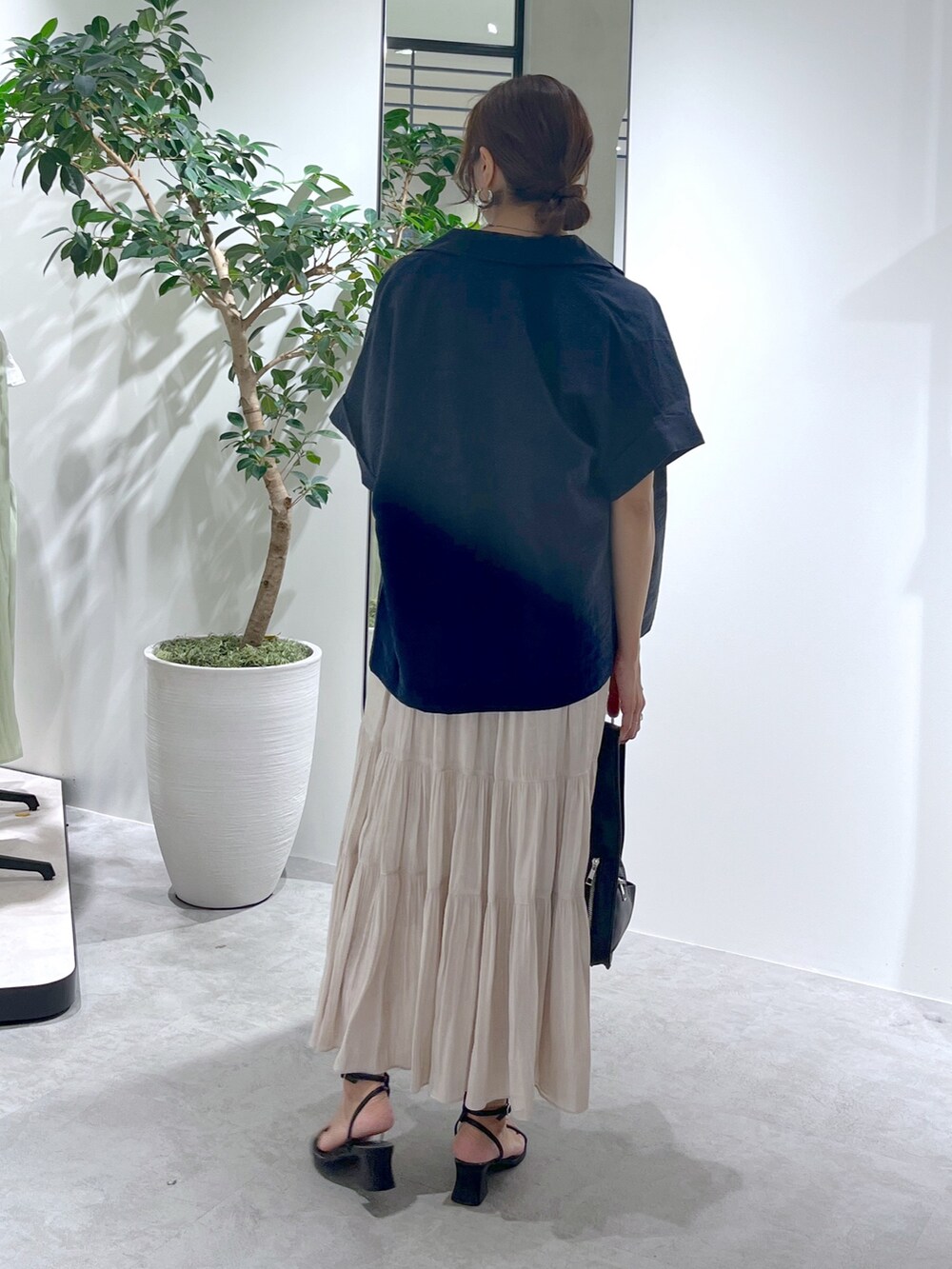 ブルー系のテーラードジャケット、ブラック系のハンドバッグ、ホワイト系のスカートを着用したレディースの夏コーディネートの7枚目の写真