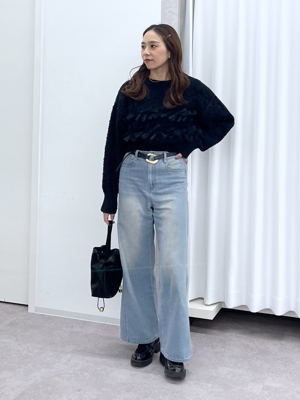 ブラック系のショルダーバッグ、ブルー系のデニムパンツ、ブラック系のニット/セーターを着用したレディースの冬コーディネートの8枚目の写真