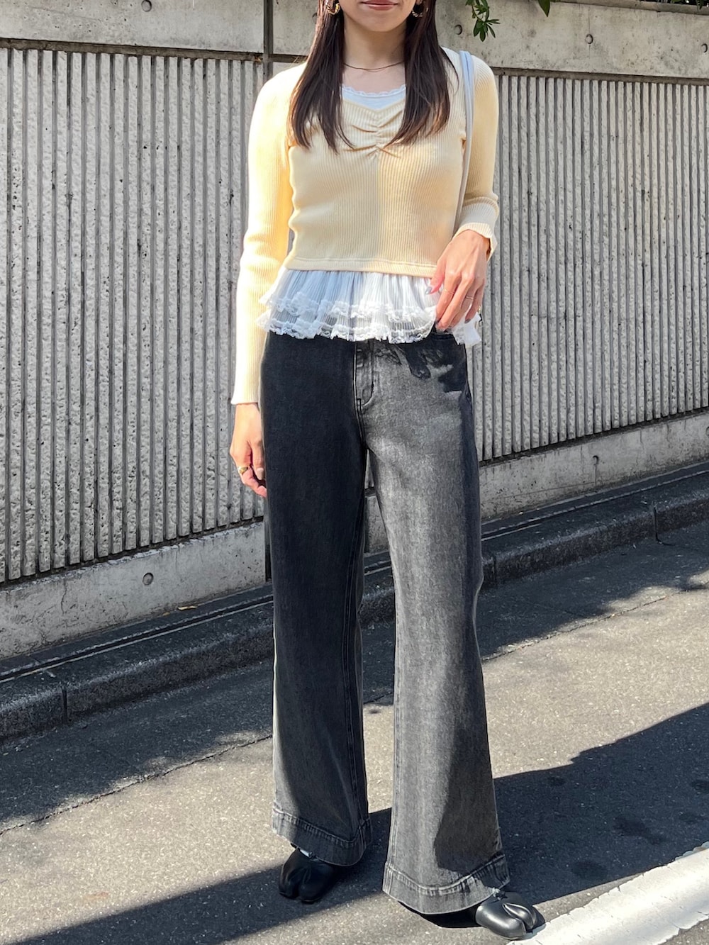 イエロー系のニット/セーター、ブラック系のデニムパンツ、ホワイト系のショルダーバッグを着用したレディースの冬コーディネートの6枚目の写真