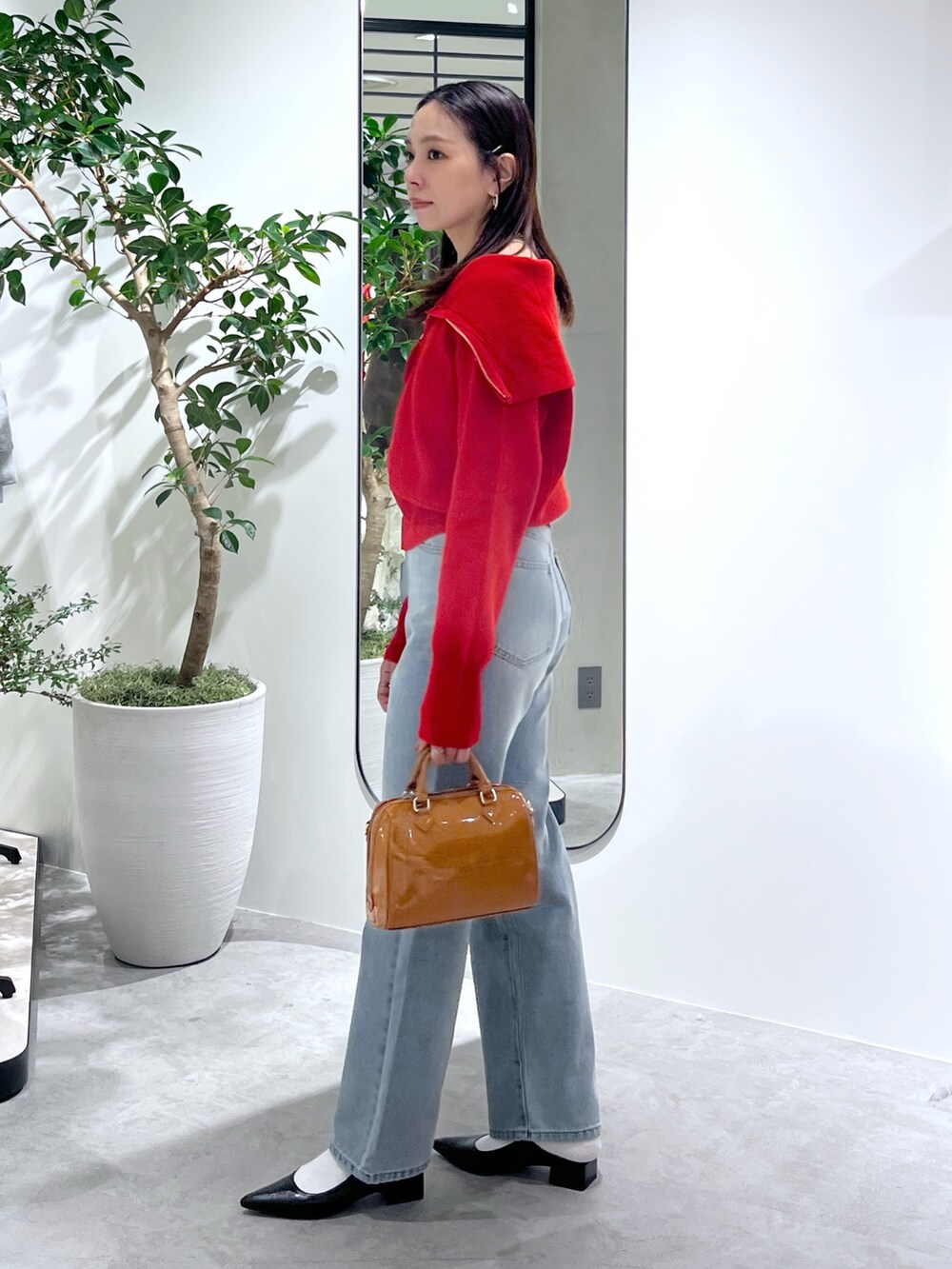 レッド系のニット/セーター、ブルー系のデニムパンツ、ベージュ系のショルダーバッグを着用したレディースの春コーディネートの7枚目の写真