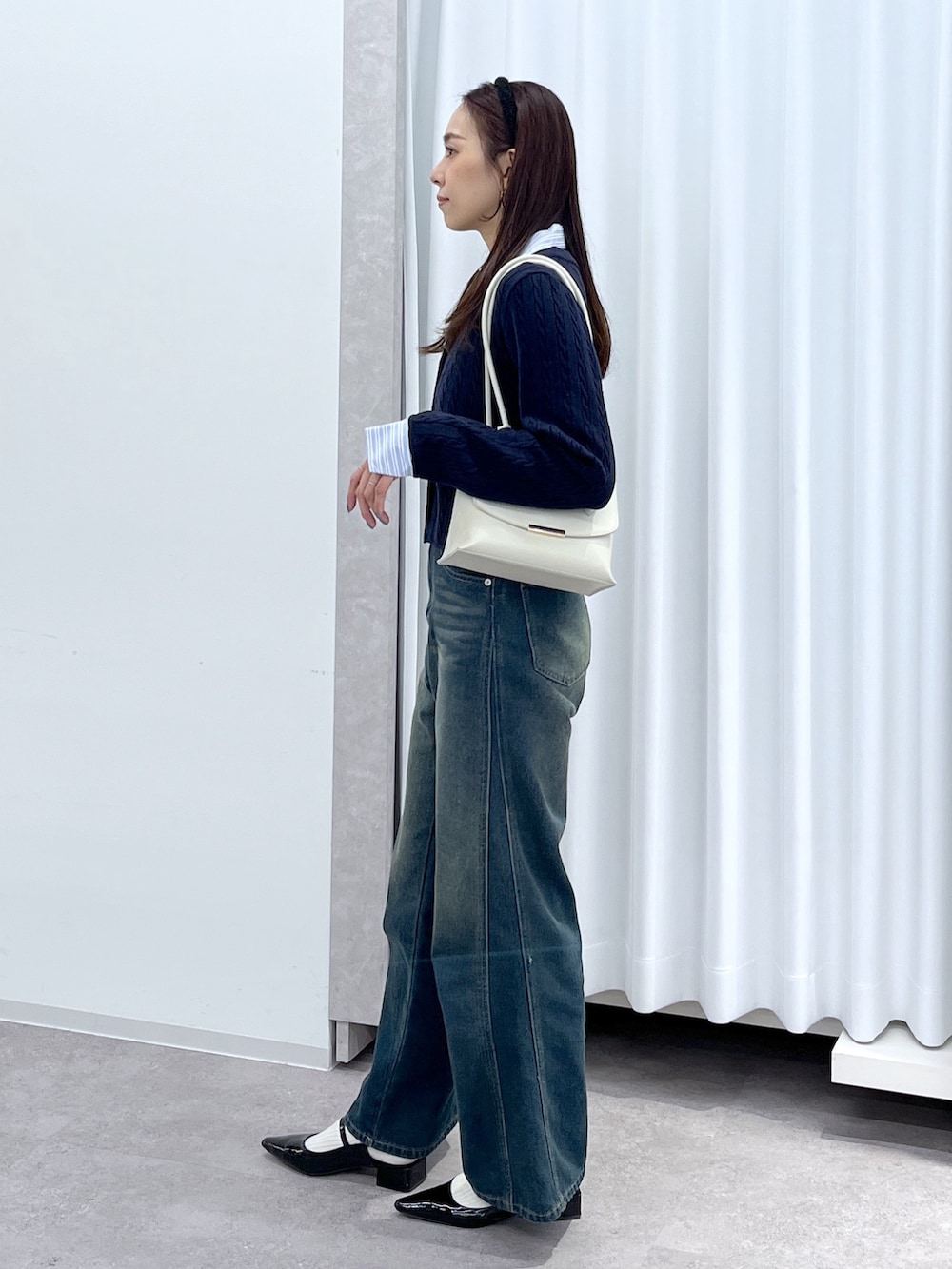 ブラック系のパンプス、ブルー系のニット/セーター、ホワイト系のショルダーバッグを着用したレディースの冬コーディネートの6枚目の写真